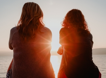 Two women watch the sunset on a beach