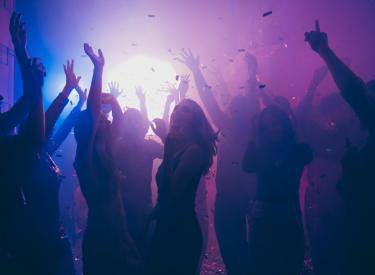 A group of friends dancing inside a club with blue and purple lights 