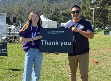 Joe and a volunteer holding a thank you sign