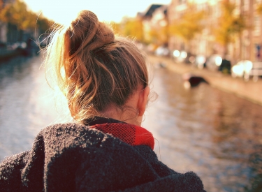A girl in a coat looks out at a river