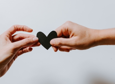 Two hands holding a cut-out of a heart. Image by Kelly Sikkema via Unsplash.