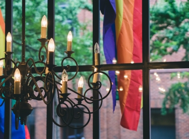 Window with candelabra and pride flag. Photo by Tatiana Rodriguez on Unsplash