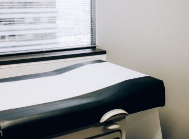 A table in a doctors office lined with paper. Photo by Charles Deluvio on Unsplash