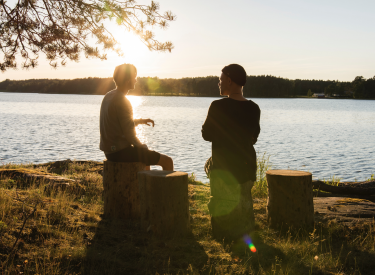 Two men talking by a lake at sunset. Photo by Aarón Blanco Tejedor on Unsplash