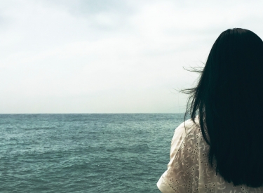 A woman with dark hair looking out at sea