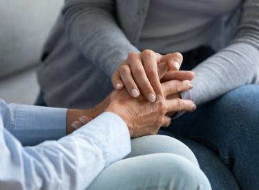 two people who are grieving hold hands
