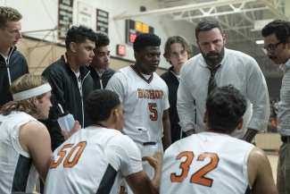Ben Affleck as Jack, wearing a shirt and tie, talking to a group of young basketball players