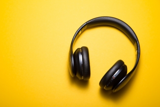 Black headphones on a yellow background. Photo by Malte Wingen on Unsplash
